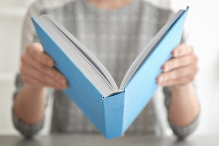 Young woman with book at tableの写真素材