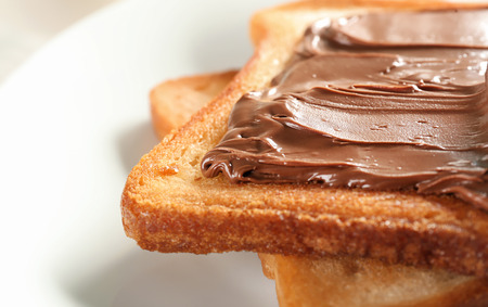 Delicious toasts with chocolate paste on plate, closeup