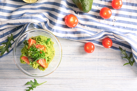 Bowl with fresh guacamole and tomatoes on wooden tableの写真素材