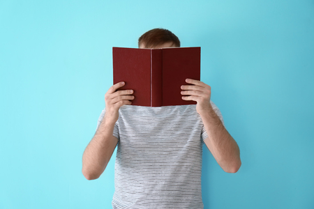 Young man reading book on color backgroundの写真素材