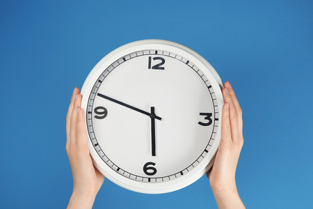 Female hands holding clock on color background. Time management conceptの写真素材