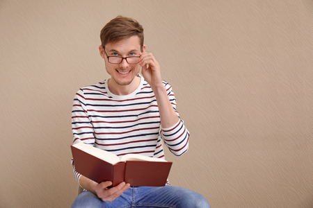 Young man reading book on color backgroundの写真素材