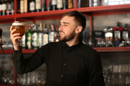 Bartender with glass of beer in barの写真素材