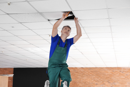 Mature electrician performing wiring in new empty apartmentの写真素材