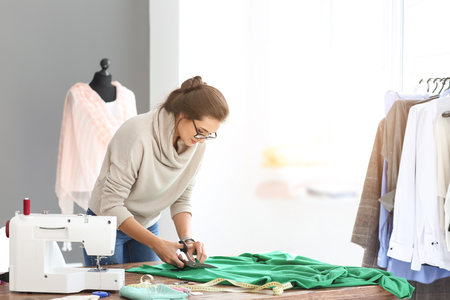 Young female tailor cutting fabric in atelierの写真素材