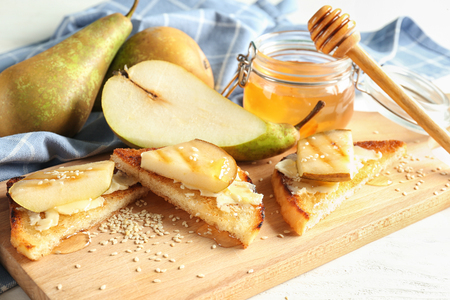 Delicious toasts with pear and honey on wooden boardの写真素材