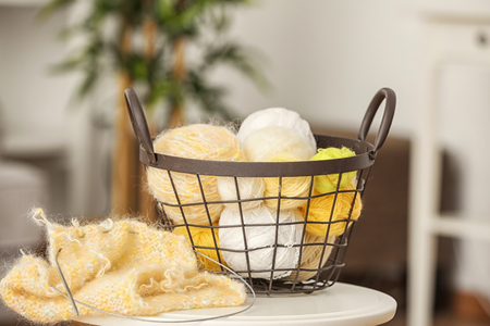 Metal basket with knitting threads on tableの写真素材