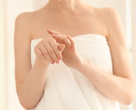 Beautiful woman applying cream in morning at homeの写真素材