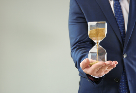 Man holding hourglass on grey background. Time management conceptの写真素材