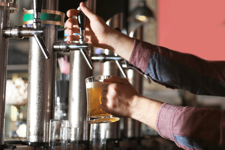 Bartender pouring beer into glass in barの写真素材