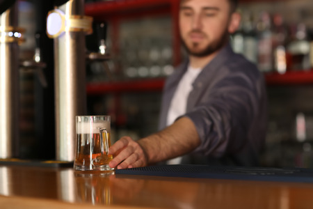 Bartender with glass of beer in barの写真素材