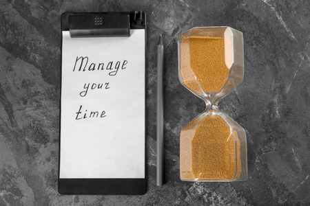 Hourglass with clipboard and pencil on grey textured background. Time management concept