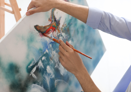 Male artist painting on canvas on white backgroundの写真素材