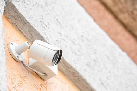 Modern CCTV camera installed on wall of building outdoors