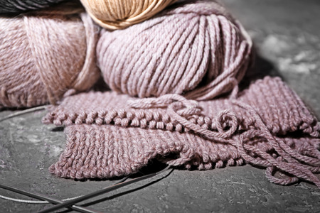 Half-finished clothes with knitting yarn on grey background