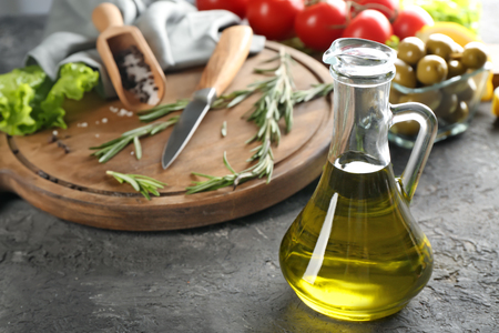 Glass jug with fresh olive oil on tableの写真素材