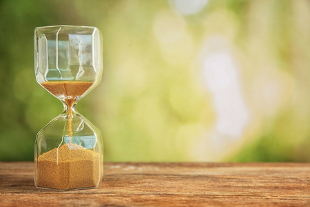 Hourglass on wooden table outdoors. Time management concept