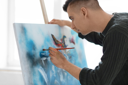 Male artist painting on canvas in workshopの写真素材