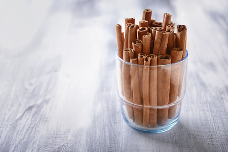 Glass with cinnamon sticks on wooden tableの写真素材