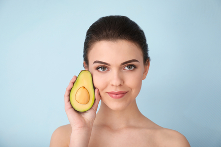 Beautiful young woman with avocado on color backgroundの写真素材