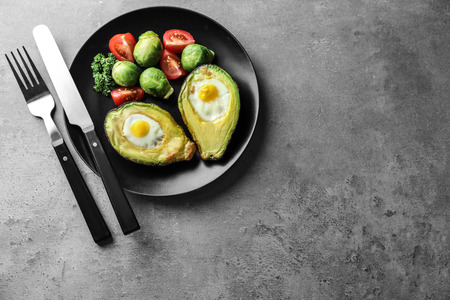 Baked avocado with eggs and vegetables on grey backgroundの写真素材