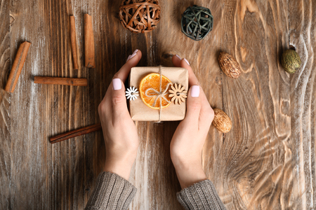 Woman holding beautiful gift box on wooden backgroundの写真素材