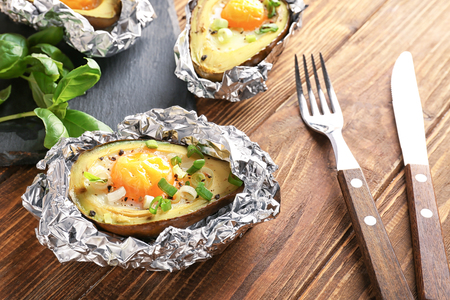 Avocado baked with egg in foil on wooden tableの写真素材
