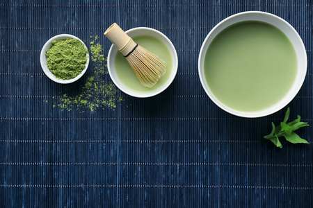 Bowls of fresh matcha tea and powder on bamboo matの写真素材