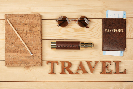 Word TRAVEL made with letters and tourist's stuff on wooden background, top viewの写真素材