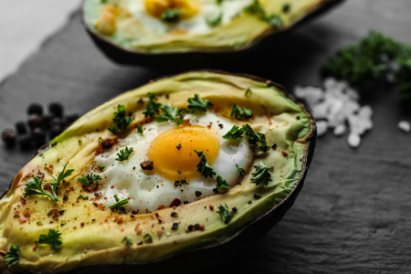 Baked avocado with egg on dark textured background, closeupの写真素材