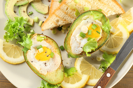 Eggs baked in avocado and slices of toasted bread on plate, closeupの写真素材