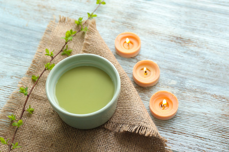 Bowl of fresh matcha tea with candles on wooden tableの写真素材
