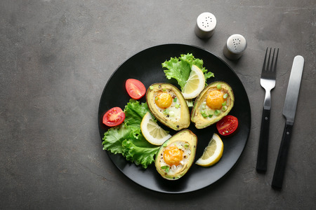 Plate with tasty eggs baked in avocado on tableの写真素材