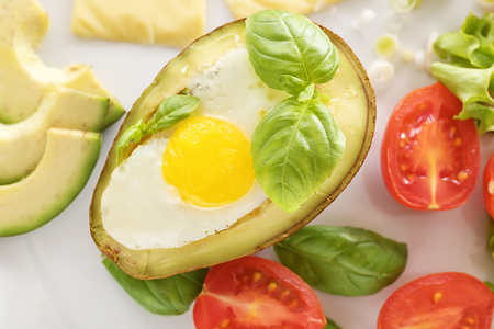 Tasty baked avocado with egg and fresh vegetables on plate, closeupの写真素材