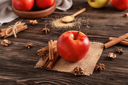 Fresh apple and cinnamon sticks on wooden tableの写真素材