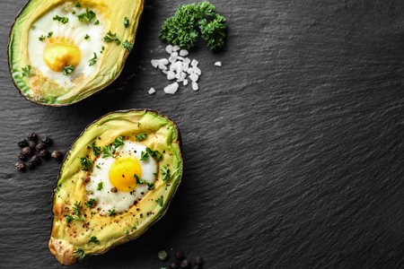 Baked avocado with eggs on dark textured backgroundの写真素材