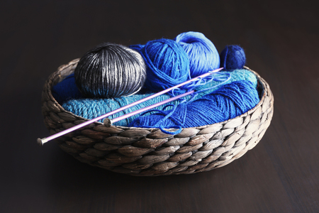 Wicker basket with knitting yarn and needles on tableの写真素材