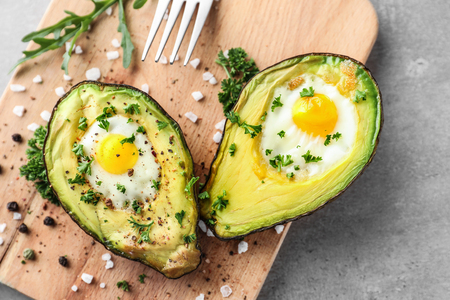 Baked avocado with eggs on wooden boardの写真素材