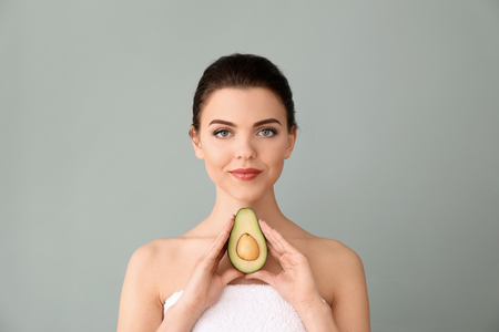 Beautiful young woman with avocado on color backgroundの写真素材