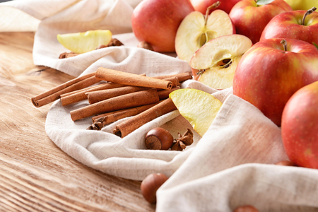Fresh apples and cinnamon sticks on wooden tableの写真素材