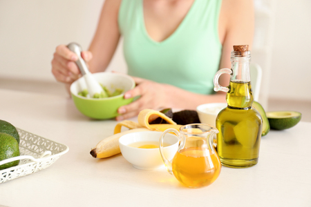 Woman making nourishing mask with avocado in kitchenの写真素材