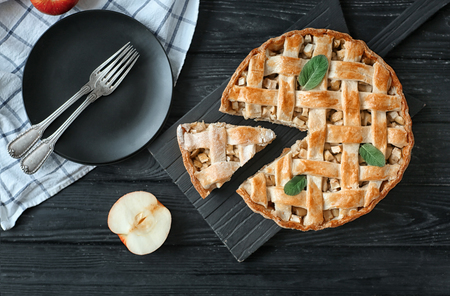 Wooden board with tasty homemade apple pie and plate on tableの写真素材