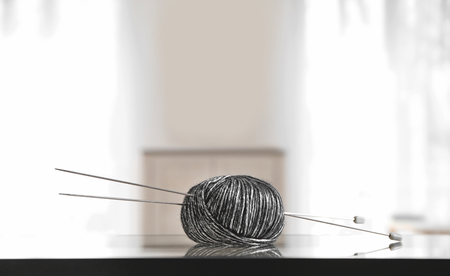 Knitting thread with needles on glass tableの写真素材
