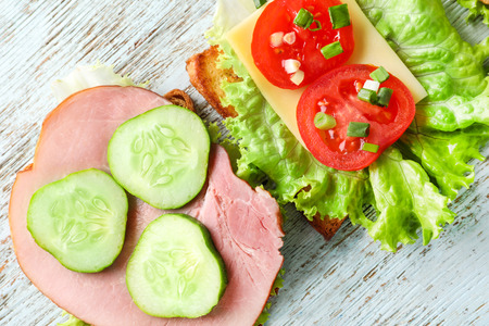 Toasted bread with ham and vegetables on wooden tableの写真素材