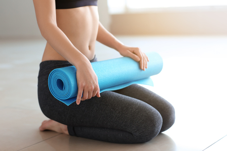Young woman with yoga mat indoorsの写真素材