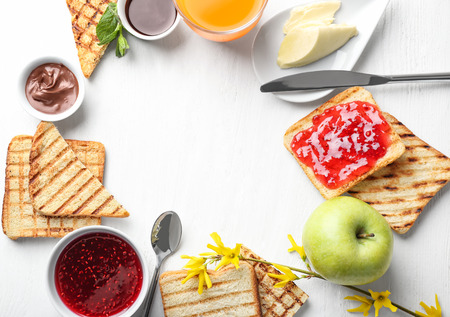 Composition of toasted bread with sweet jam, butter and chocolate paste on white table