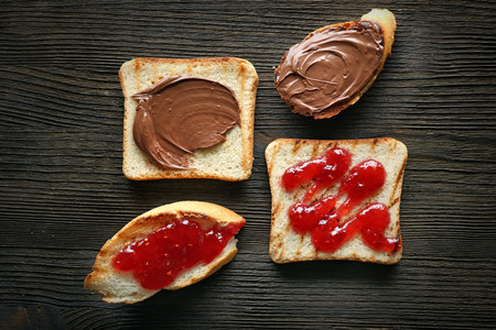 Delicious toasts with jam and chocolate paste on wooden tableの写真素材