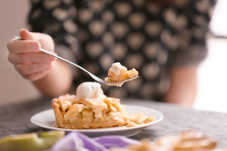 Woman eating tasty apple pie in kitchenの写真素材