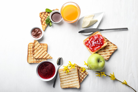 Composition of toasted bread with sweet jam, butter and chocolate paste on white tableの写真素材