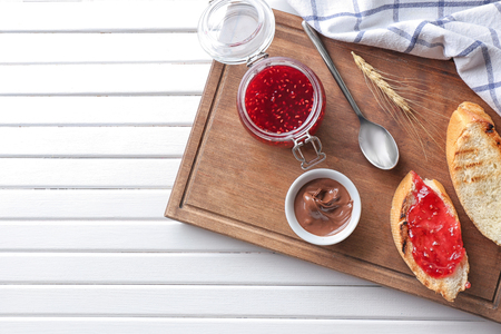 Toasted bread with jam and chocolate paste on wooden boardの写真素材